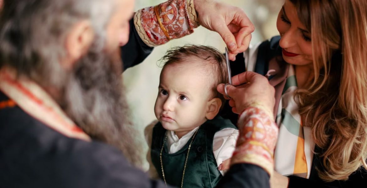 A baby's first haircut performed during a religious ritual with parents and clergy present.