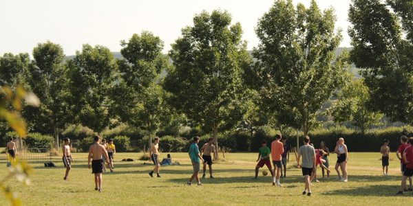 a group of people standing on top of a lush green field