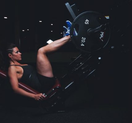 A woman engages in an intense leg press workout at the gym, showcasing strength and fitness.